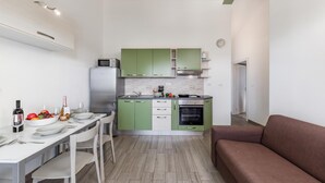 A compact kitchen with a dining area, a microwave, a refrigerator, and a built-in oven. - Wabi Sabi Apt8 Pool & Sea View, Brzac, Croatia (Brzac)
