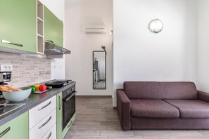 Eine moderne Küche mit grünen Schränken, einem Herd und einem Essbereich mit braunem Sofa.