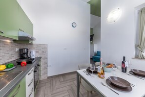 A compact kitchen with a dining area, a clock on the wall, and a view into a living space. - Wabi Sabi Apt7 Pool & Sea View, Brzac, Croatia (Brzac)