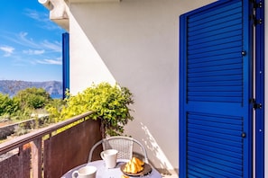 A balcony with a table, chairs, and a view of the landscape.