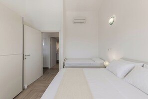 Ein Hotelzimmer mit einem Bett, einem Nachttisch mit Lampe, einem Kleiderschrank und einer Klimaanlage.