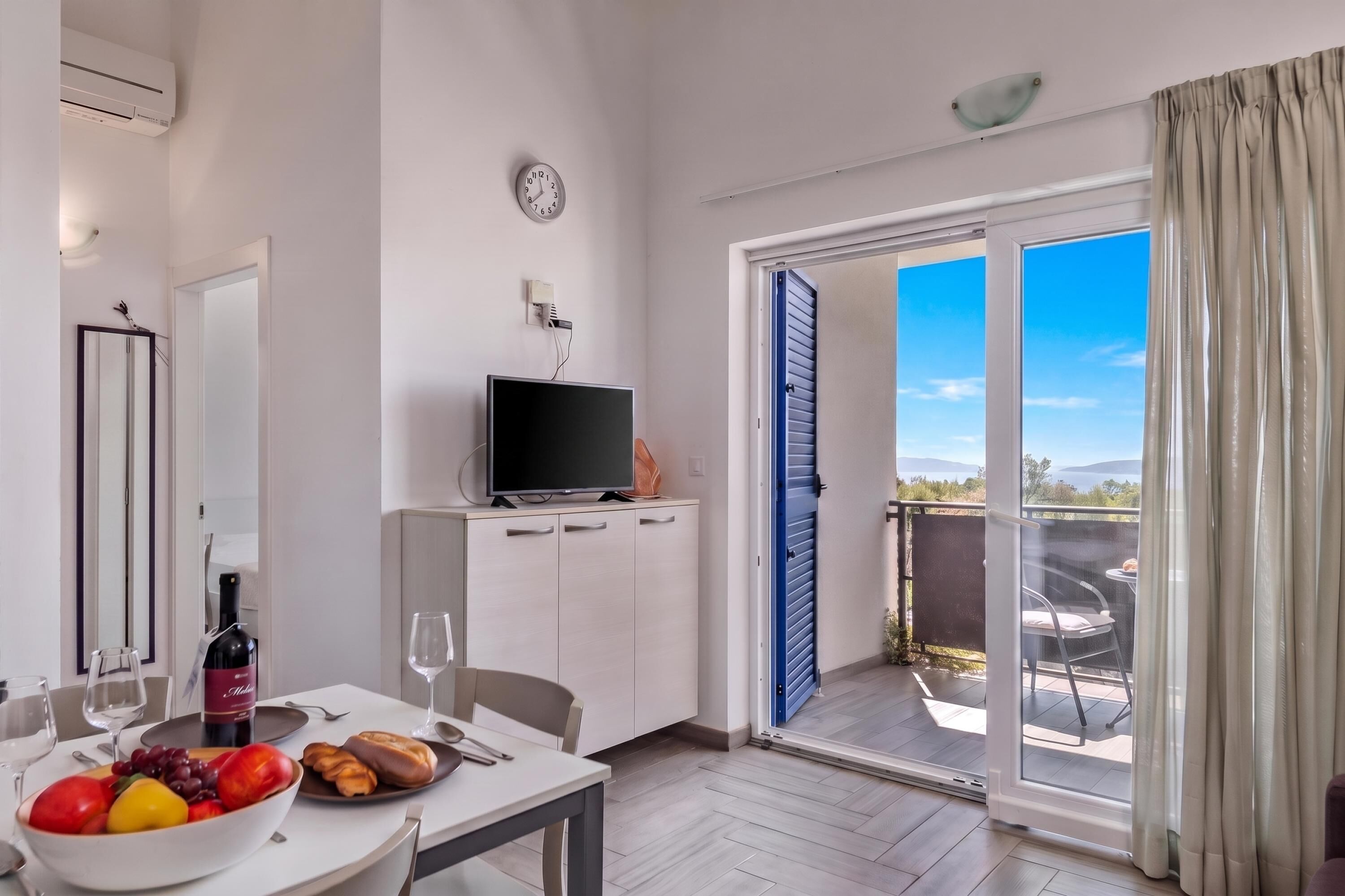 Ein modernes Hotelzimmer mit Essbereich, Fernseher und einem Balkon mit Blick.