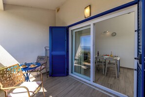Eine Außenpatio mit Tisch und Stühlen, eine Schiebetür und Blick in den Innenbereich mit Essbereich.