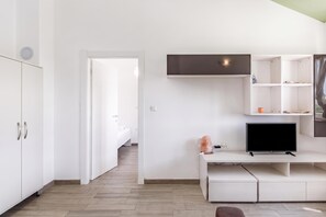 A modern, minimalist room with a bed, a desk with a TV, and a shelving unit. - Wabi Sabi Apt3 Pool & Sea View, Brzac, Croatia (Brzac)