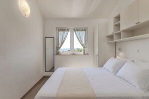 Ein Schlafzimmer mit Bett, einem Fenster mit Vorhängen, einem Nachttisch und Einbauschränken.