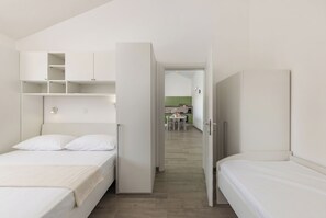Ein Schlafzimmer mit Bett, Kleiderschrank und einer Küchenzeile im Hintergrund.