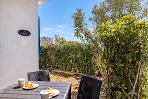 An outdoor dining area with a table and chairs, a sign on the wall, and a hedge in the background. - Wabi Sabi Apt6 Pool & Garden, Brzac, Croatia (Brzac)