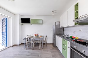 Une cuisine compacte comprenant un coin repas, un téléviseur encastré et un réfrigérateur.