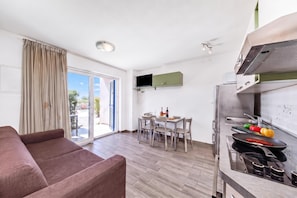 A modern apartment with a dining area, kitchenette, and a sofa. - Wabi Sabi Apt6 Pool & Garden, Brzac, Croatia (Brzac)