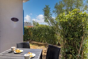 Ein Tisch im Freien mit Tellern, Tassen und einem Stuhl, sowie ein Schild an der Wand.