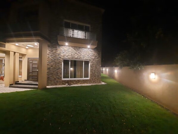 A two-story building with a stone facade, a large window, and a well-lit entrance.