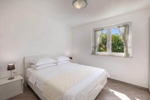 Ein Schlafzimmer mit einem Bett, Nachttischen, einer Lampe und einem Fenster mit Vorhängen.