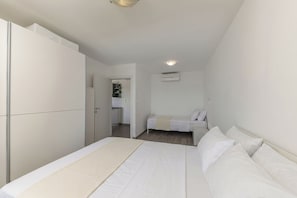Ein Schlafzimmer mit Bett, Kleiderschrank, einer Küchenzeile und einem Badezimmer.