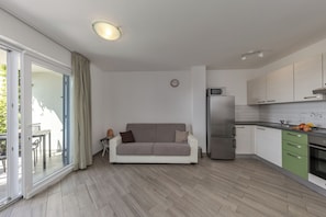 Eine moderne Küche mit Kühlschrank, Mikrowelle und grünen Schränken.