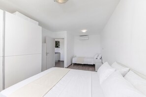 Een slaapkamer met een bed, een kledingkast, een kleine kitchenette en een plafondlamp.