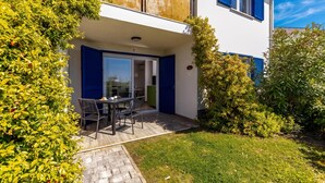 A two-story building with a balcony, a dining area with chairs and a table, and a well-maintained garden. - Wabi Sabi Apt2 Pool & Garden, Brzac, Croatia (Brzac)