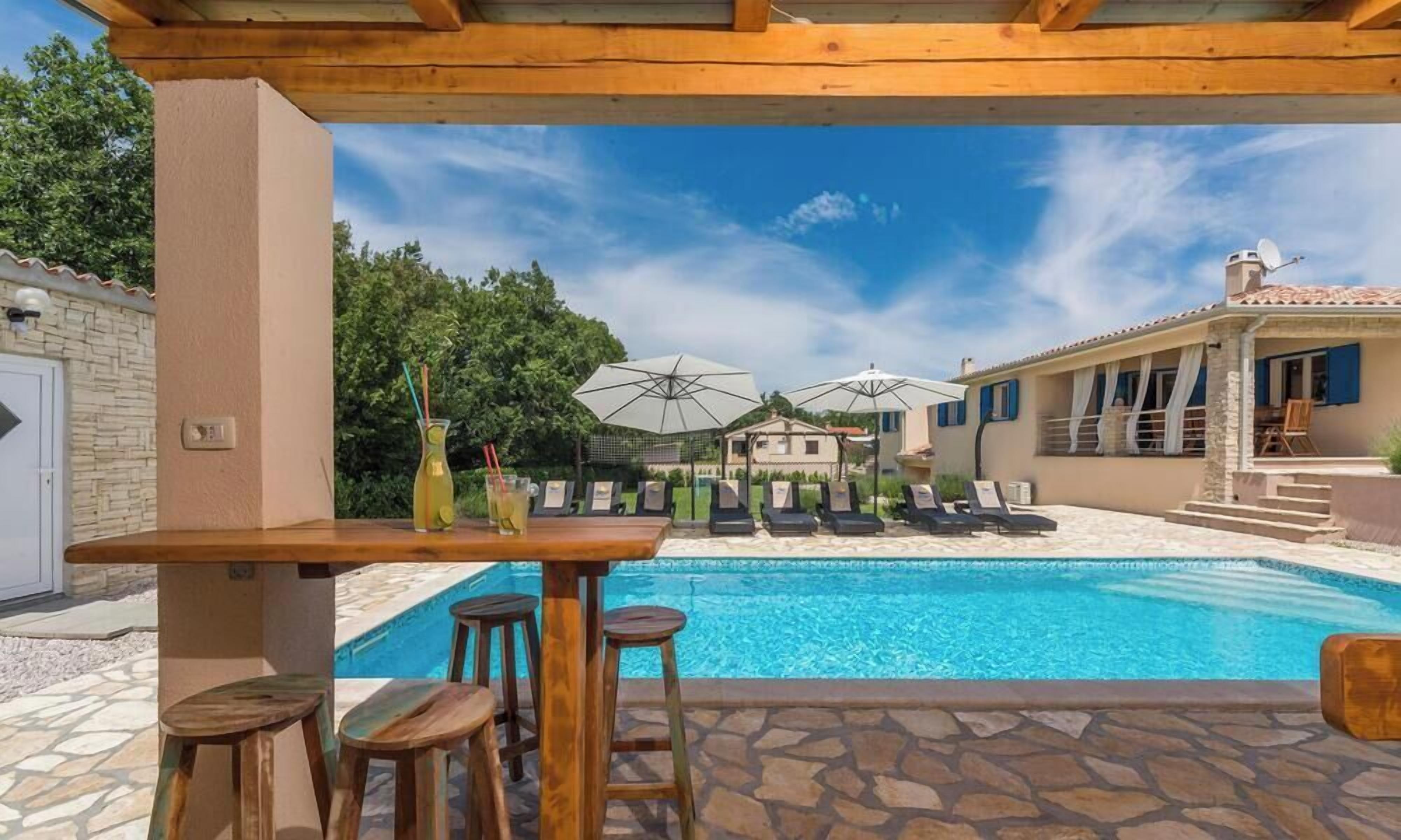 A poolside area with a bar, lounge chairs, and umbrellas.