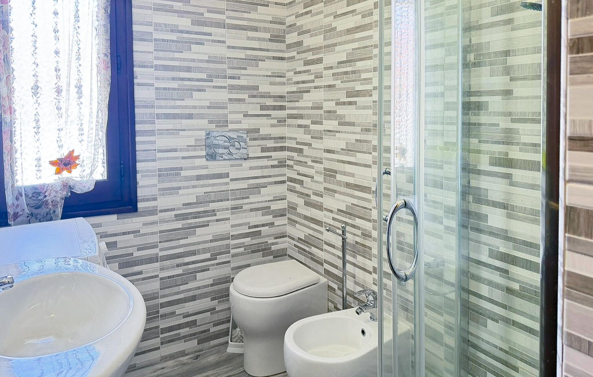 Un baño con cabina de ducha de vidrio, inodoro y lavamanos.