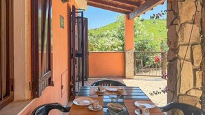 En uteservering med ett bord för fyra personer, en träpergola och utsikt över en sluttning.