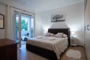 Ein Schlafzimmer mit einem Bett, Nachttischen, einem Beistelltisch, einem weißen Teppich und einem Bild an der Wand.