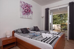 A hotel room with a bed, a nightstand, a lamp, a painting, and a view of the outdoors.