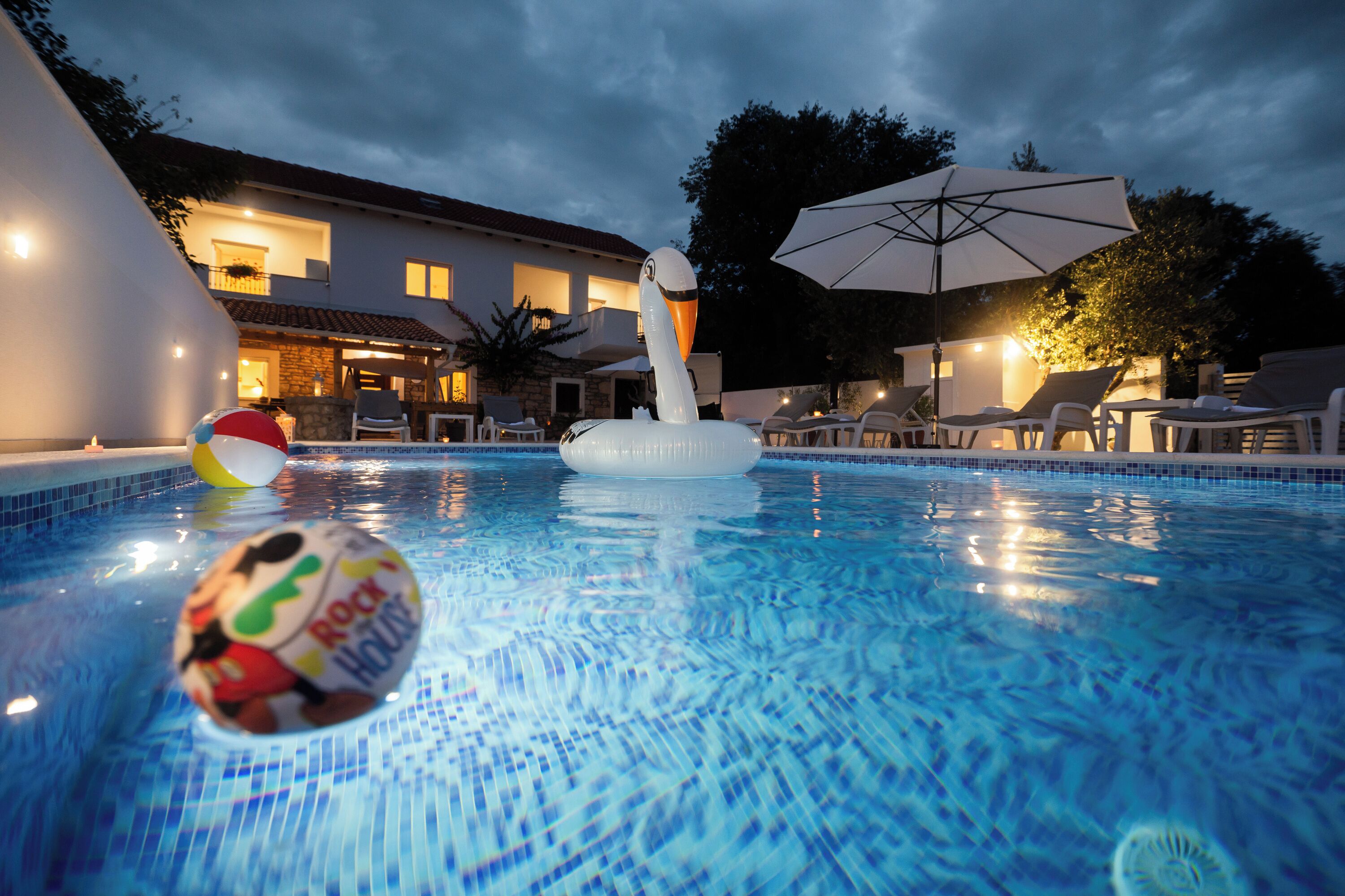 A swimming pool with inflatable toys, lounge chairs, and umbrellas.