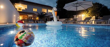 A swimming pool with inflatable toys, lounge chairs, and umbrellas.