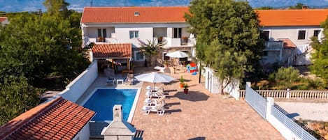A residential property with a swimming pool, outdoor seating, and a view of mountains.