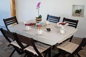 A round dining table with a white tablecloth, surrounded by six wooden chairs with cushioned seats.