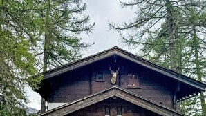 Eine Holzhütte mit einem an der Dachspitze befestigten Hirschgeweih, zwei Garagentoren und einem Schild, das daraufhinweist, dass es sich um ein Ferienhaus handelt.