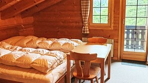 Ein gemütliches Schlafzimmer in einer Blockhütte mit einem Bett, einem Holztisch und einem Fenster.