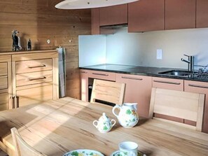 A wooden kitchen with a table, cabinets, and a sink. - Zum Hirsch - upper floor by Interhome (Bellwald)