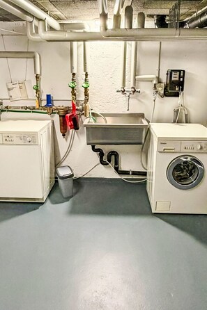 Ein Waschraum mit Waschmaschine, Spüle sowie verschiedenen Rohren und Ventilen.