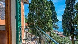 Un balcó amb vista al mar i als arbres del voltant.