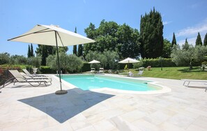 Une piscine entourée d’un jardin aménagé, avec des chaises longues et des parasols.