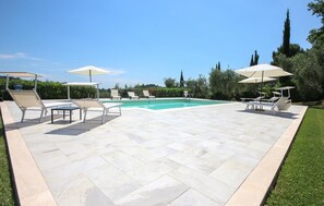 Un espace piscine équipé de chaises longues et de parasols.