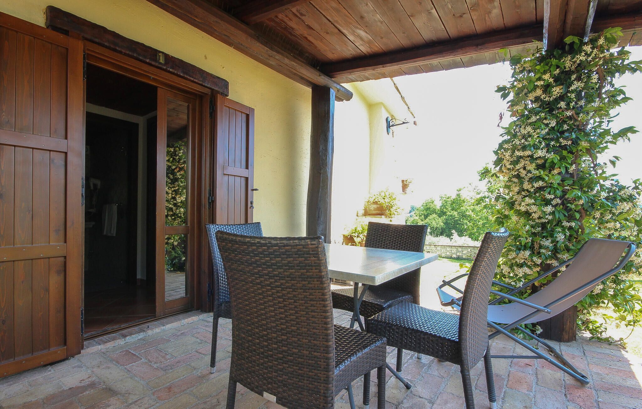An outdoor patio with wicker furniture, a table, and a wooden door.