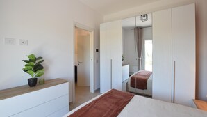 Ein Schlafzimmer mit Bett, Schminktisch, Spiegel und einer Topfpflanze.