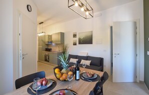 Eine moderne Küche mit Essbereich, inklusive Tisch gedeckt mit Obst und Wein, einer Couch und einer Pflanze.