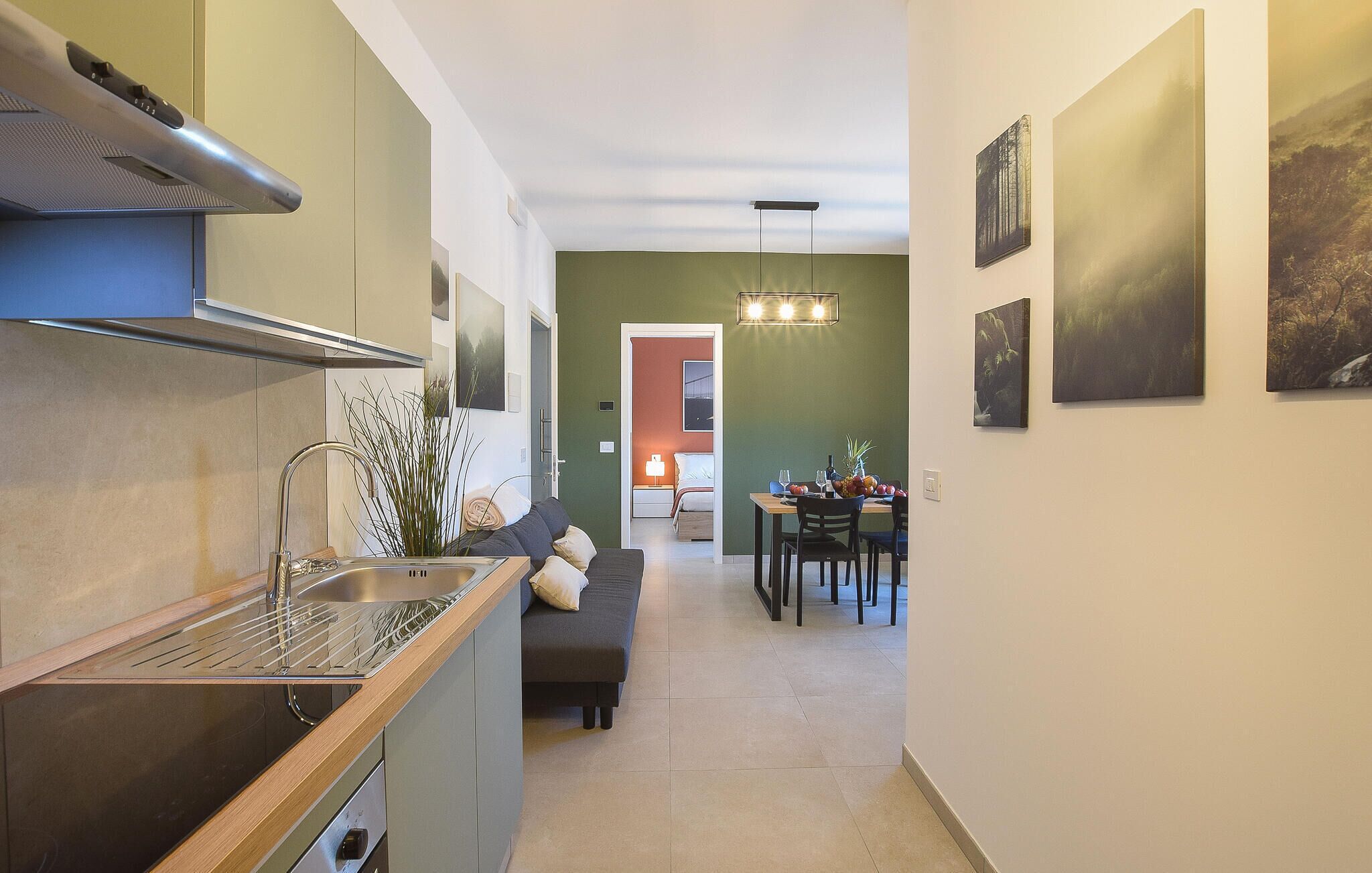A modern kitchen with a built-in oven, a dining area with a table and chairs, and a hallway leading to a bedroom.