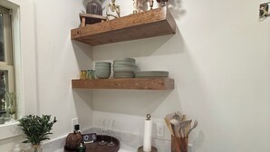 Une cuisine avec des étagères en bois, une cuisinière, un évier et divers ustensiles de cuisine.