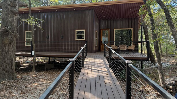 Une cabane en bois dotée d’une terrasse, entourée d’arbres.