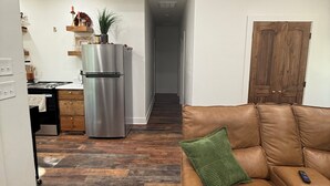 Un salon avec un canapé en cuir marron, un coussin vert et une télécommande posée dessus.