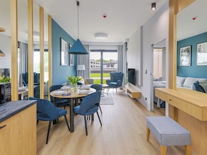 Une chambre d’hôtel moderne dotée d’un coin repas, d’une télévision et d’une grande fenêtre donnant sur l’extérieur.