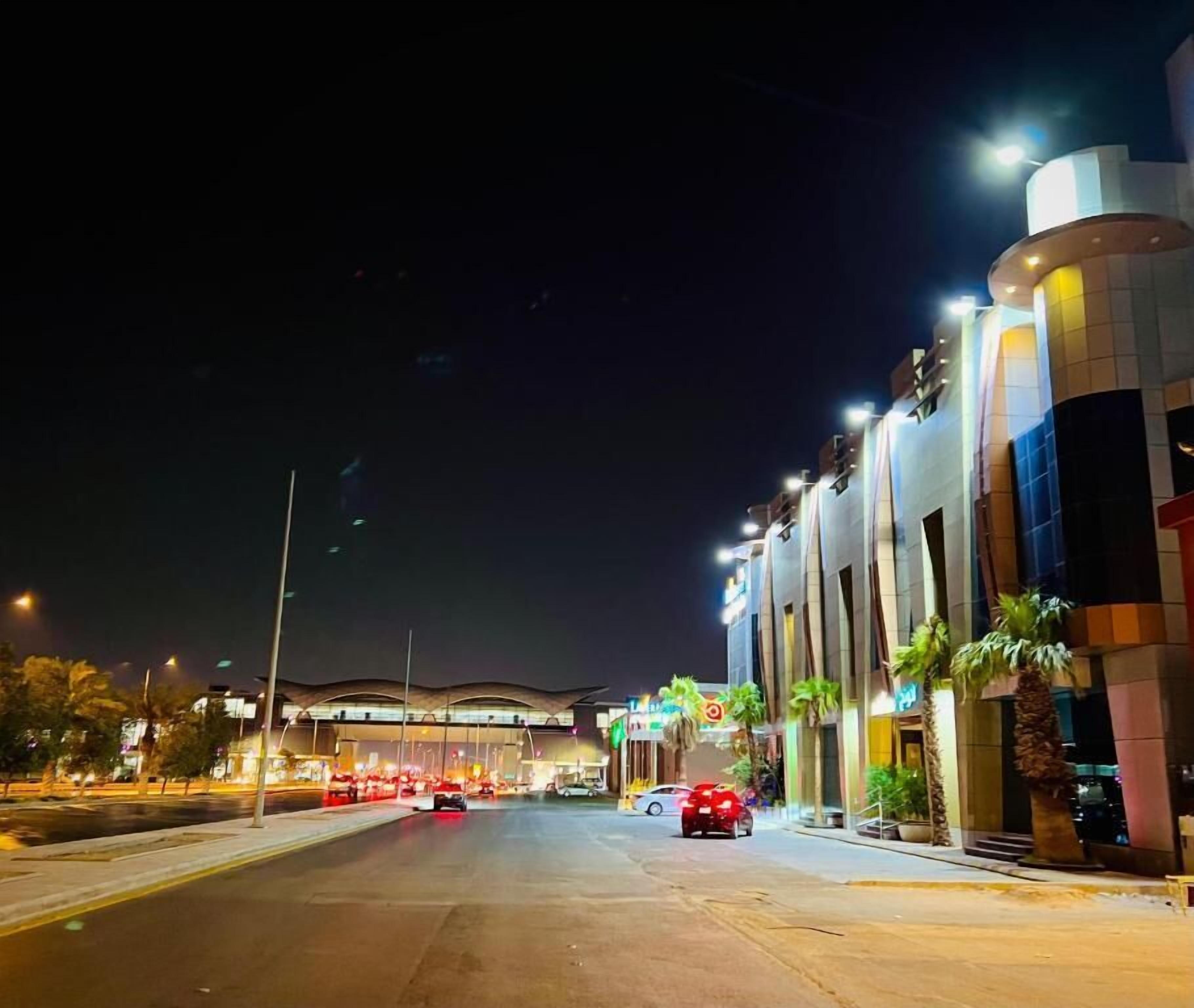 A modern building with a curved facade, illuminated by streetlights, and a clear sky.