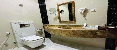 Une salle de bain équipée de toilettes, d’un lavabo, d’un miroir et d’un porte-serviettes.