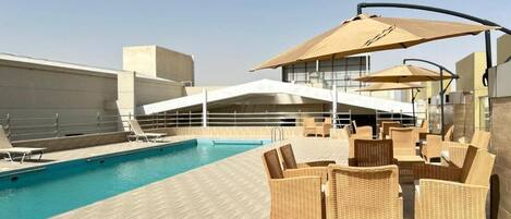 A rooftop pool area with lounge chairs and umbrellas.