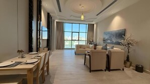 A modern living room with a dining area, large windows, and a painting on the wall. - Lavera inn Hotel (Riyadh)