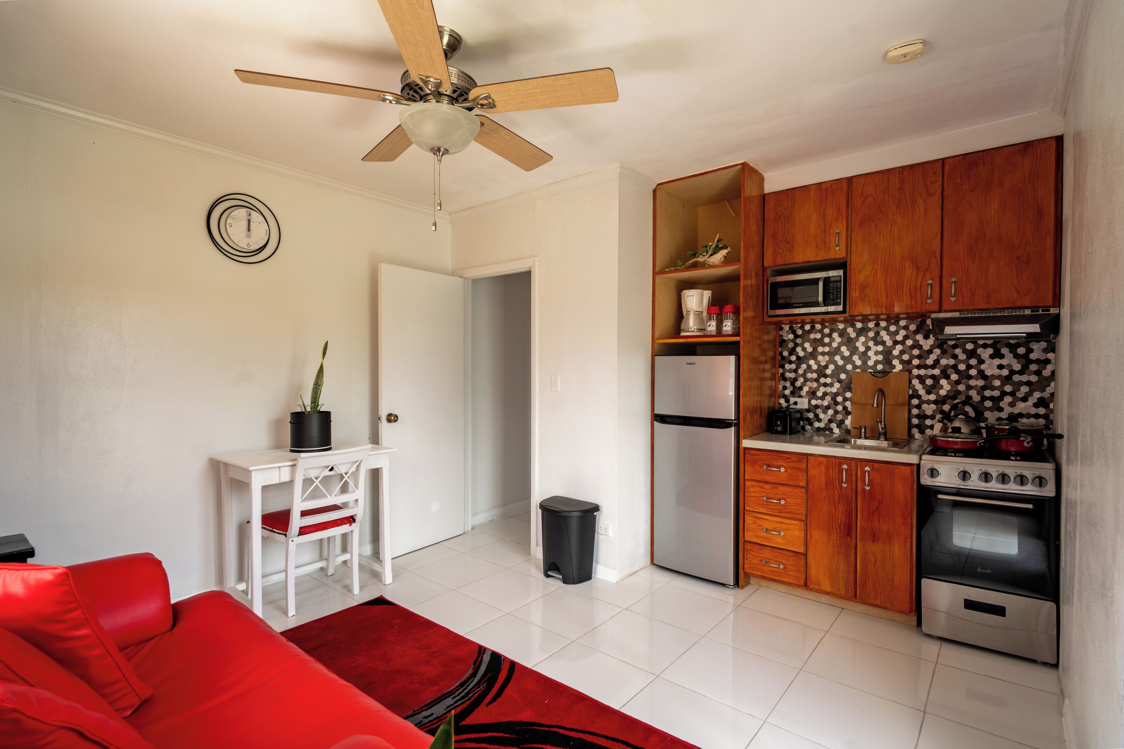 A compact kitchen with a refrigerator, microwave, oven, and wooden cabinets.