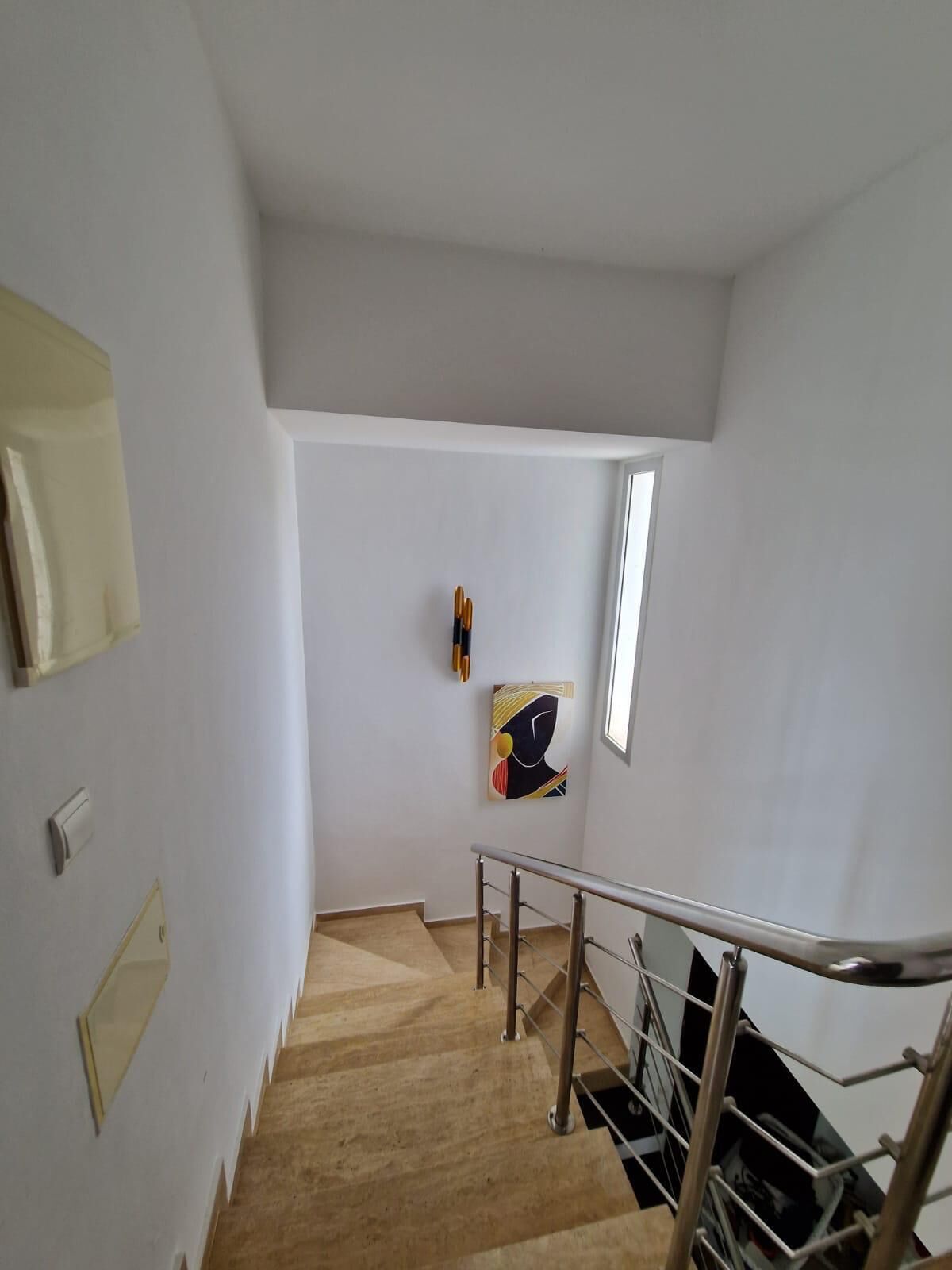 Una escalera con barandilla de metal, suelo de madera y una obra de arte colgada en la pared.